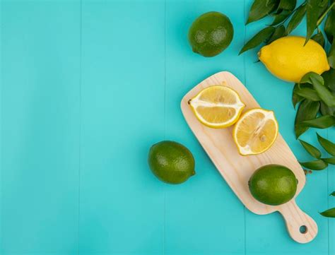 Top view of fresh and colorful lemons with green leaves on wooden ...