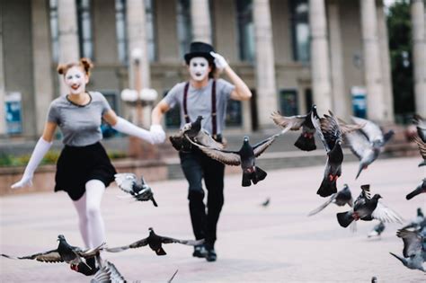 Flying pigeons near running mime couple | Free Photo