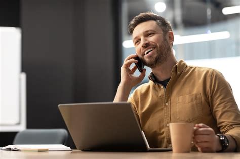 Cara de negócios falando ao telefone usando laptop sentado no local de ...