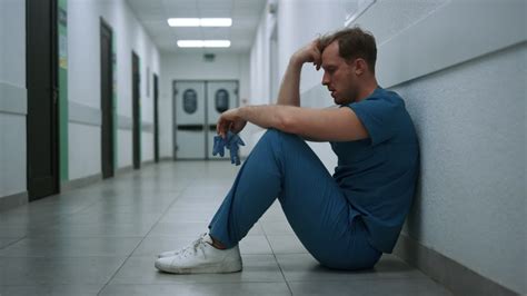 Stressed surgeon staying clinic hallway after operation. Doctor sitting ...