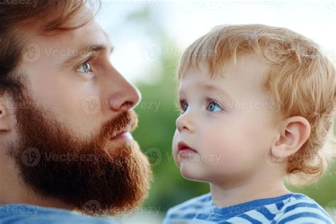 un padre miradas cariñosamente a su curioso niñito en un soleado día en ...