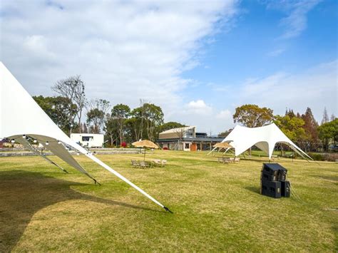 Scenic outdoor event space with elegant canopy tents and lush greenery ...
