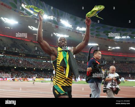 Jamaican's Usain Bolt holds his shoes after winning the 200-meter final ...