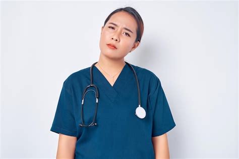 Épuisé jeune infirmière asiatique portant un uniforme bleu avec un ...