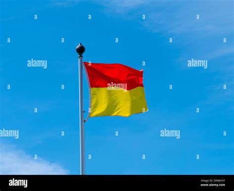 A red and yellow flag allowing swimming on the beach. flag on a blue ...