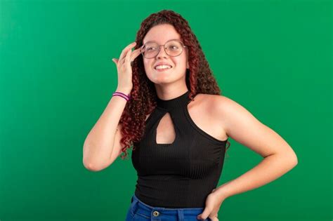 Teenager wearing glasses in fun poses in a studio photo with a green ...
