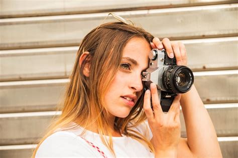 Side view of young woman photographing with digital camera | Free Photo