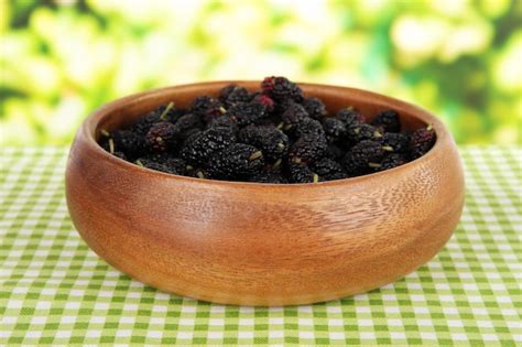 Ripe mulberries in bowl on table on bright background | Premium Photo