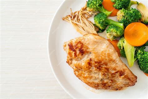 Bistec de pollo a la parrilla con vegetales en plato blanco | Foto Premium