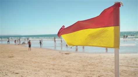 Red and yellow safety flag fluttering in breeze on sandy beach 50390001 ...