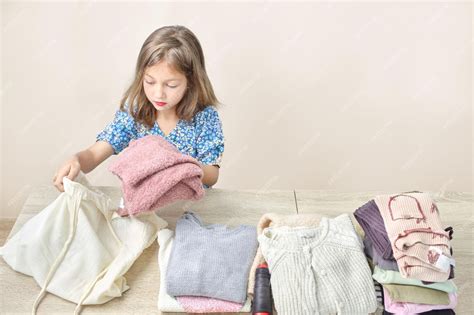 Cute caucasian little girl happily organizing her clothes for donation ...