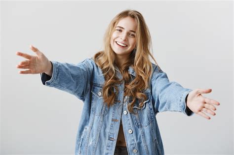 Jolie fille blonde souriante heureuse et écarter les mains sur le côté ...