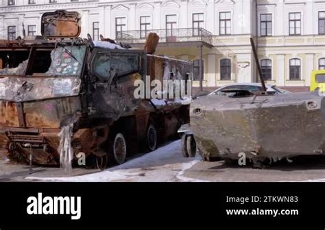 A man walks past a burnt armoured personnel carrier near buildings destroyed in the course of Ukrain