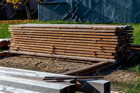 A pile of lumber is laying on the ground in front of a house. | Premium ...