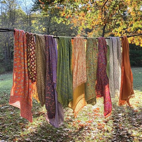 A line of colorful scarves hanging on a line with trees in the ...