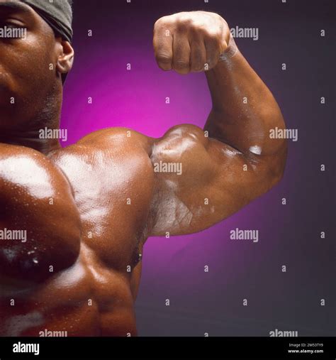 African American muscleman flexing his arm, dramatic lighting, oiled up ...