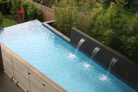 Swimming pool with water feature wall and backdrop of Bamboo plantings ...