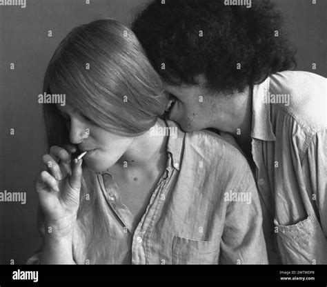 Young long-haired couple smoking weed, man kissing the back of the ...