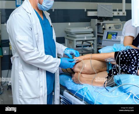 Der Arzt legt ein Pulsoximeter auf den Finger einer älteren Frau. Ein Arzt mit Maske und ...