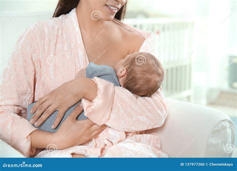 Young Woman Breastfeeding Her Baby in Nursery Stock Photo - Image of ...