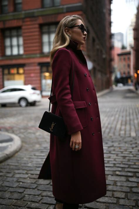 Mary Orton wears long burgundy coat, black sunglasses, black saint ...