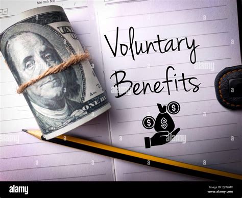 A top view of a pencil, banknotes and a text "Voluntary Benefits" on a notebook background Stock ...