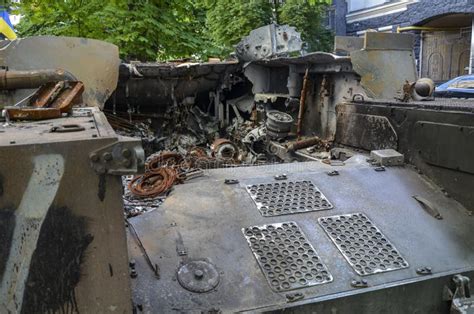A man walks past a burnt armoured personnel carrier near buildings destroyed in the course of Ukrain