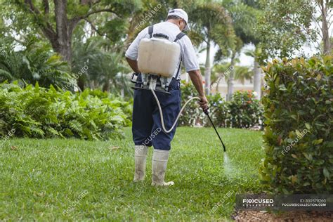 Pest control technician with portable spray rig using spray nozzle and hose — pipe, tank - Stock ...