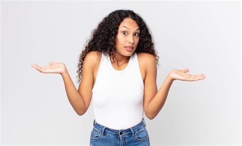 Pretty hispanic woman looking puzzled, confused and stressed, wondering ...