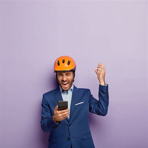 Outragé homme d'affaires posant en costume élégant et casque rouge au ...