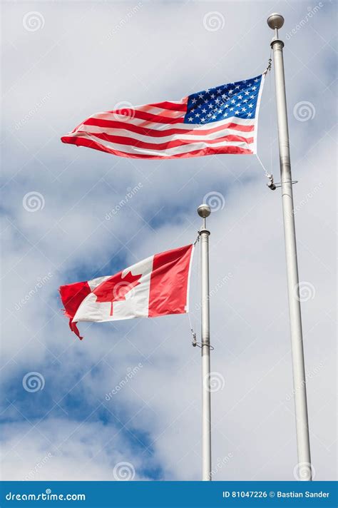 American and Canadian Flag on Poles Hanging on a Flag Pole in Th Stock ...