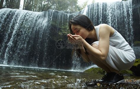 站在小溪边享受瀑布的女人用手捧水喝高清图片下载-正版图片502071684-摄图网