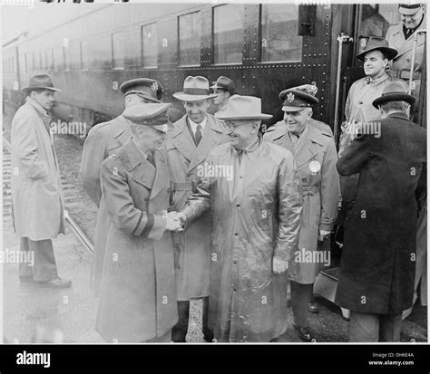 A photograph shows President Truman being greeted by military officers ...
