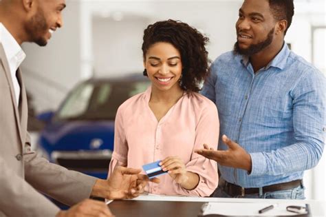 Couple buying car giving credit card to salesman in dealership ...