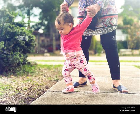 Baby’s first steps outdoors. Baby walking being helped by adult Stock ...