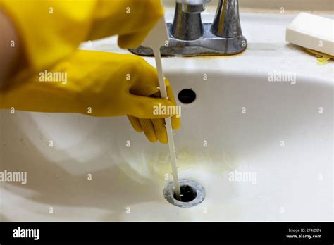 A person is trying to unclog the drain of a sink using plastic ...