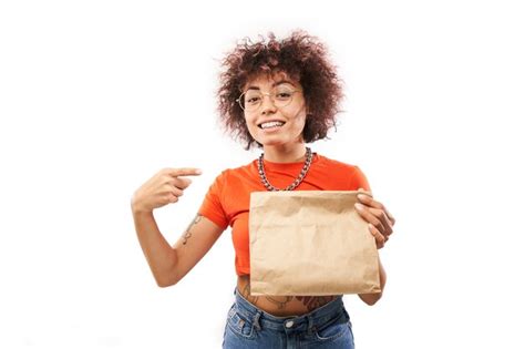 Young joyful woman with afro curls in orange clothes holding craft ...