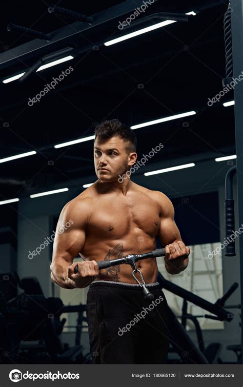Muscular bodybuilder doing exercises on cable crossover machine — Stock Photo © juriymaslak ...
