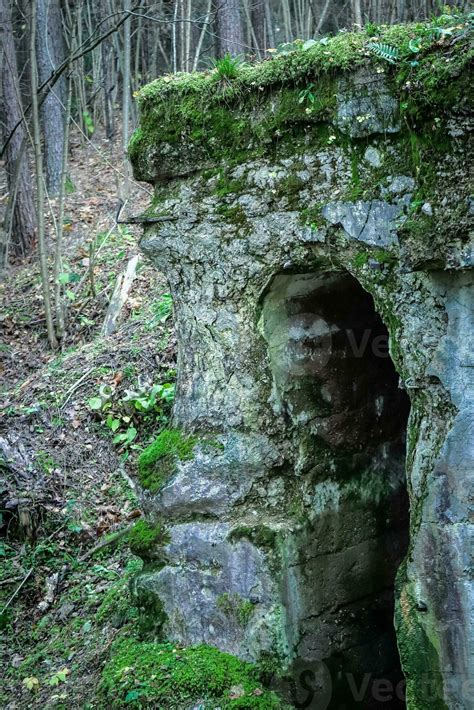 Open dark spooky entrance to the mossy catacomb with peeling concrete ...
