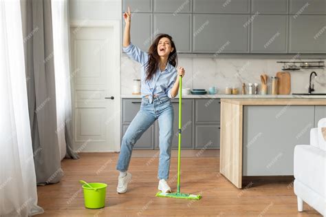 Premium Photo | Joyful young woman dancing with mop in stylish kitchen