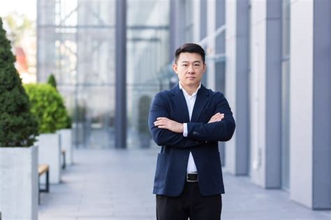 Successful asian boss near office looking at camera with crossed arms ...