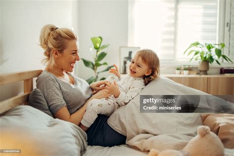 Mother and daughter cuddling on a bed in a kids room