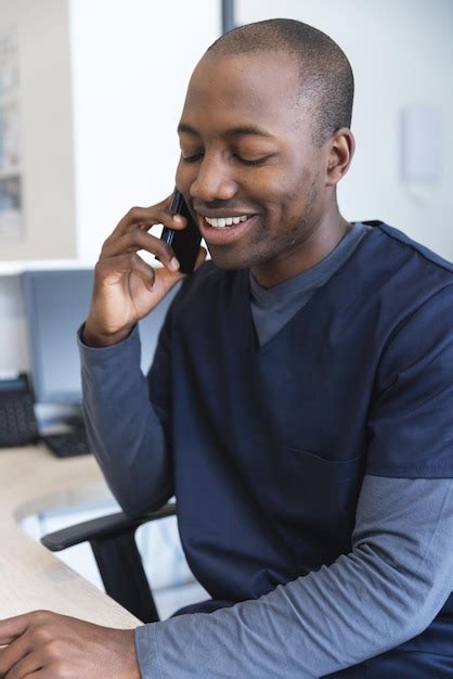 African american male doctor talking on smartphone at reception desk in ...