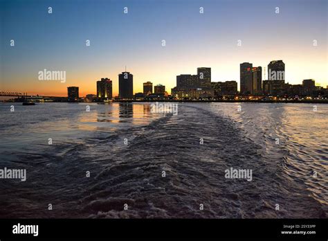 The New Orleans skyline is illuminated at sunset, with the Mississippi ...