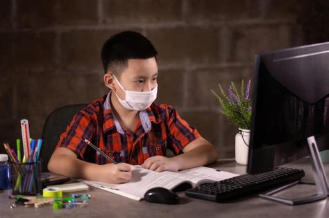 Happy boy studying with face mask on table at home | Premium Photo
