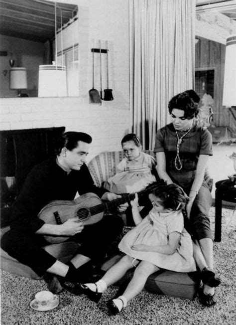1957: Country singer/songwriter Johnny Cash holds a guitar as his wife ...