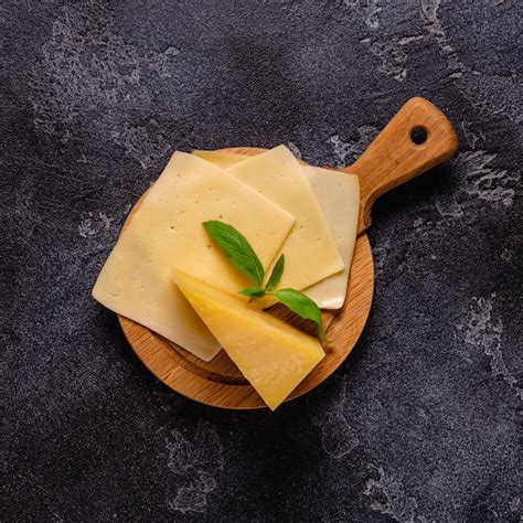 Piece of cheese and slices of cheese on a board | Premium Photo