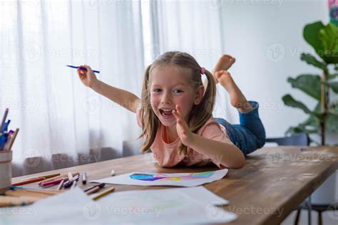 With smile 5-year-old girl giggles while creating art at the table with ...
