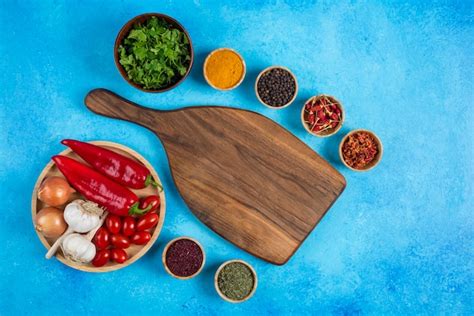 Diverse kruiden rond houten bord met plaat van groenten. | Gratis Foto