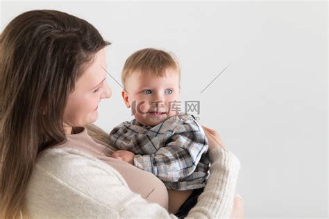 白色背景中，年轻的白人妇女怀里抱着微笑的婴儿高清摄影大图-千库网